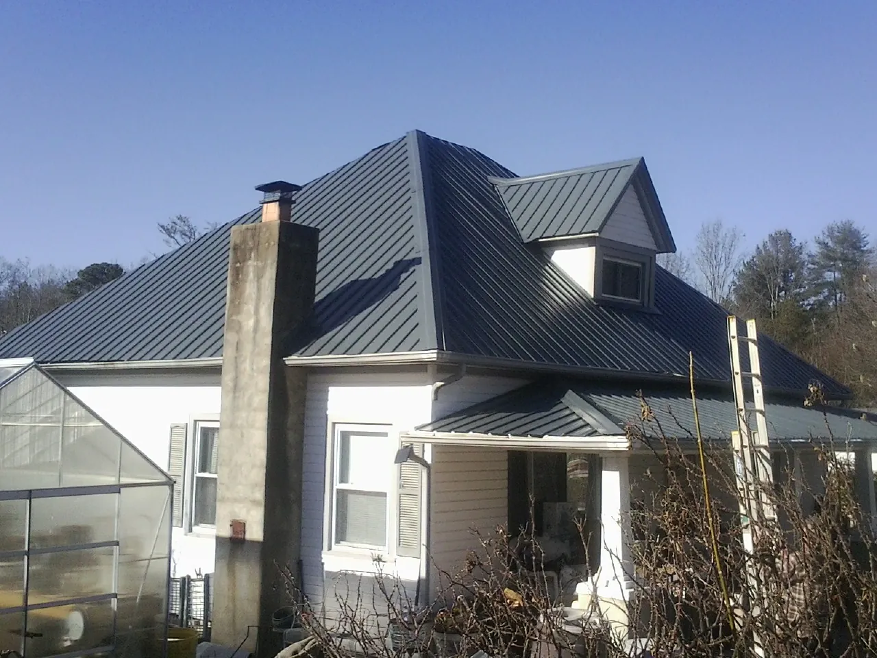 Dark blue standing seam metal roof on a white farmhouse with dormer — Slate & Tile Roof Repair by Roofing Brothers in Cranberry