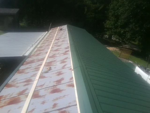 Old rusted panels beside newly installed green metal roofing — Wind Damage Roof Repair by Roofing Brothers in Cranberry