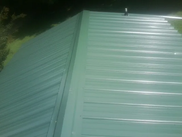 New green metal panels meeting at the ridge of a roof — Flat Roof Repair work by our crew in Cranberry
