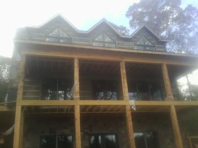 Dormers and porch framing on a large log home under construction — Roof Coating work by our crew in Cranberry