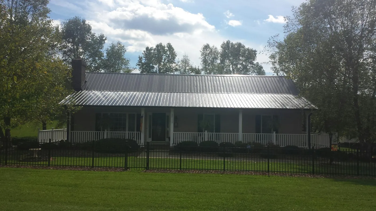 Gray metal roof on a brick ranch with a full width front porch — Gutter Guard Installation work by our crew in Cranberry