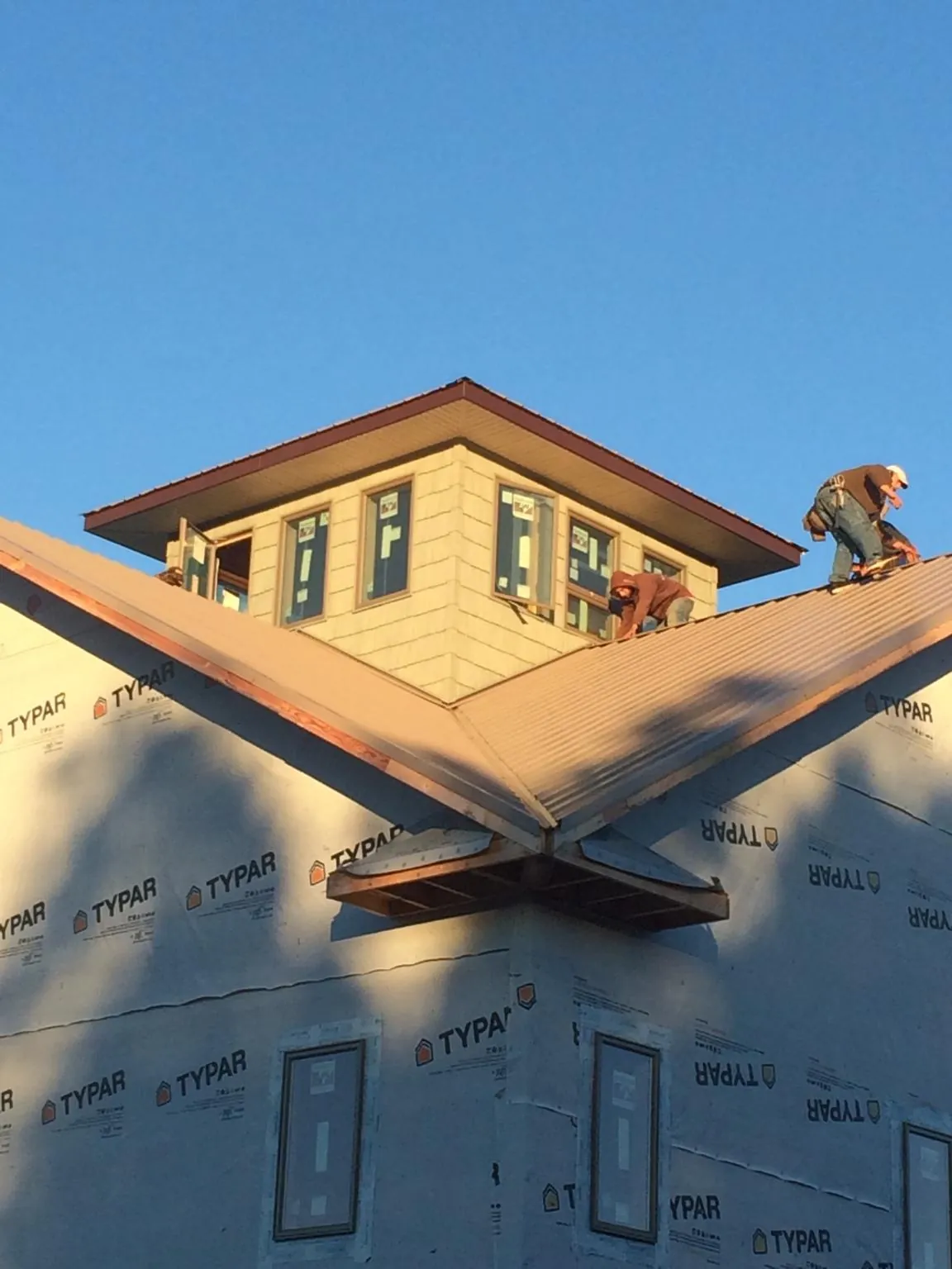 Roofers working around a rooftop cupola on a new metal roof at sunset — Roof Waterproofing in Cranberry by Roofing Brothers